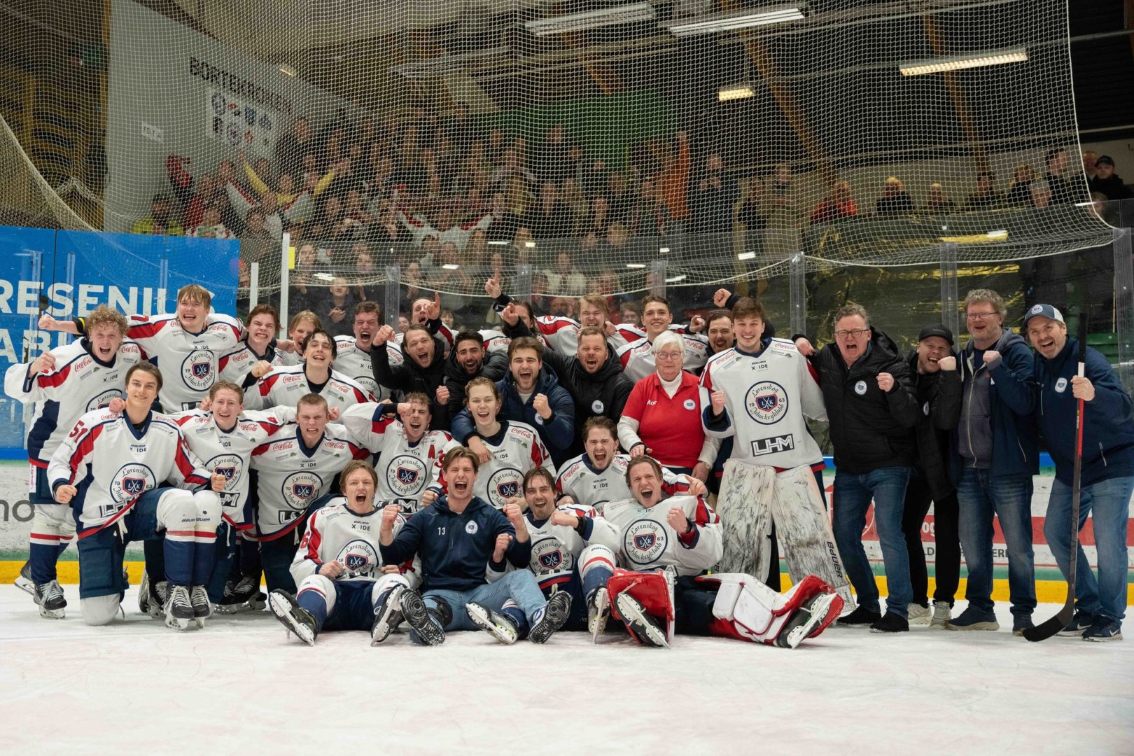 Spillerne fra Lørenskog ishockeyklubb heier foran et bilde, med fans i bakgrunnen